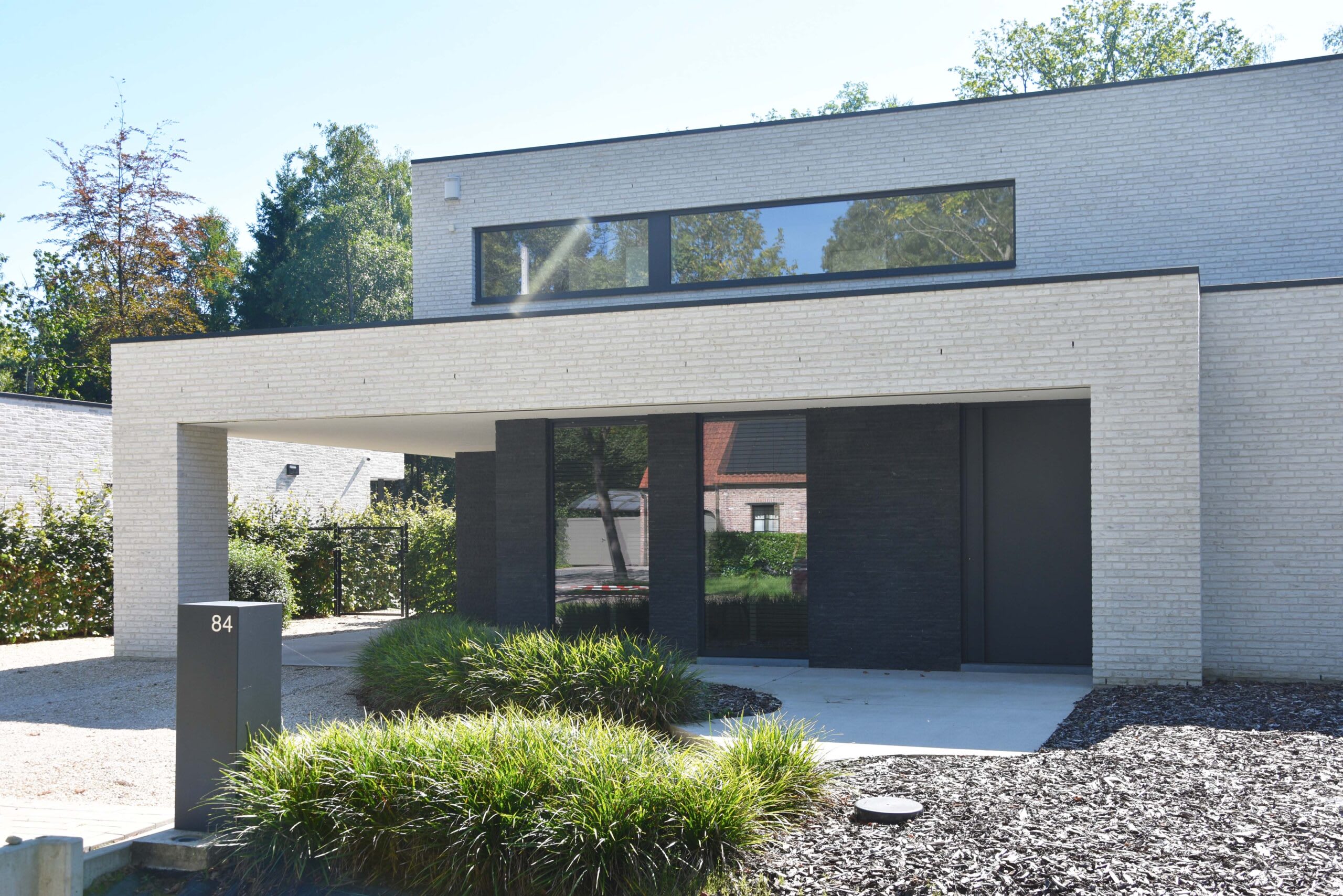 Exterior of a light grey brick house with some light landscaping